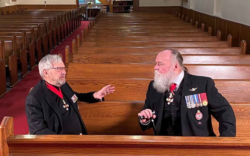 Colonel Andrew Nellestynin and Paul Cane sitting in pews