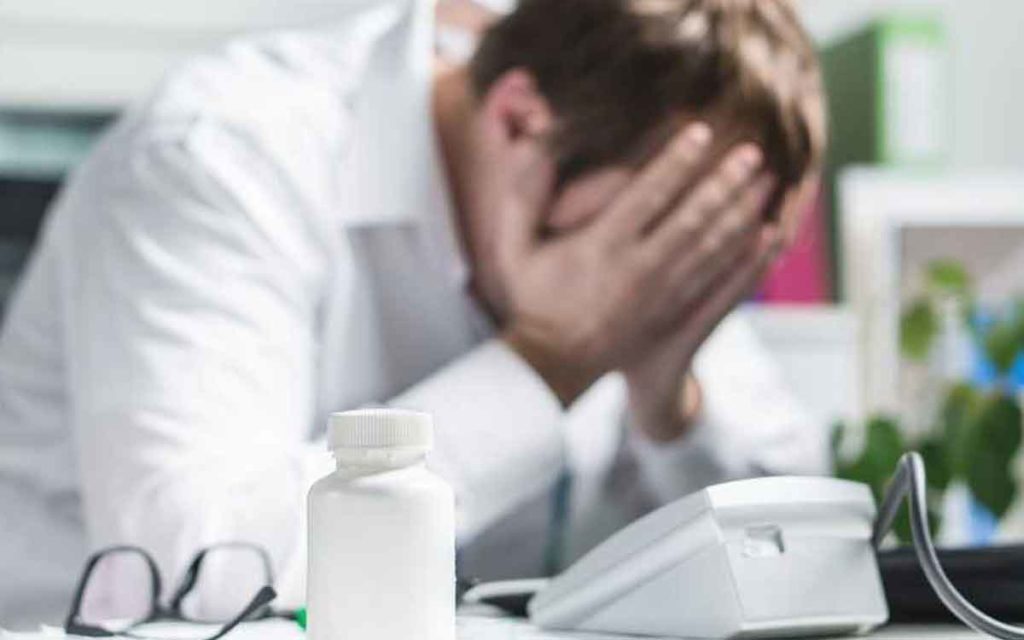 man sitting at desk with his hands on his face 