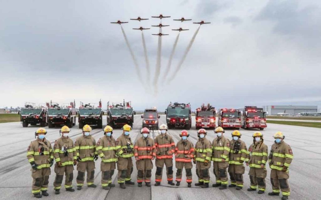 snowbirds flying over a group of firefighters