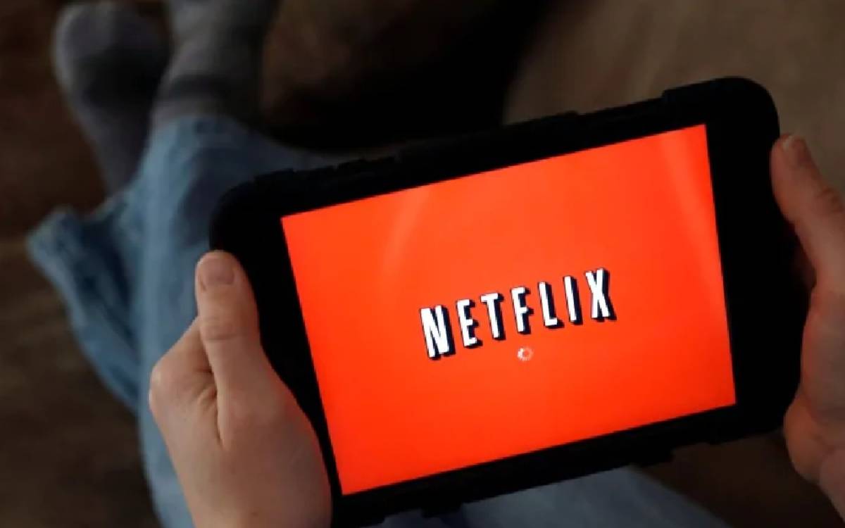 A person holding a tablet with Netflix displayed