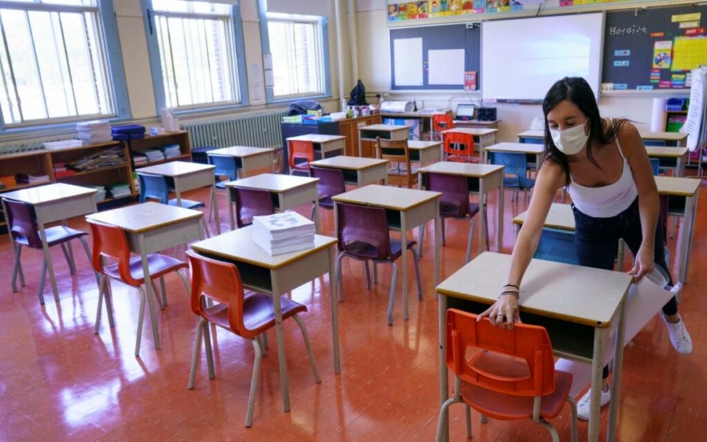 a teacher cleaning desks in a classroom