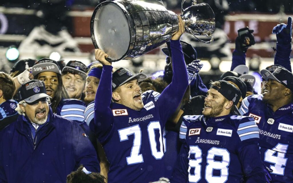 Lirim Hajrullahu hoists the Grey Cup